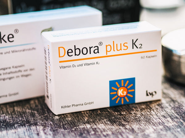 Produktverpackung von Debora plus K2 von Köhler Pharma auf hölzerner Fläche