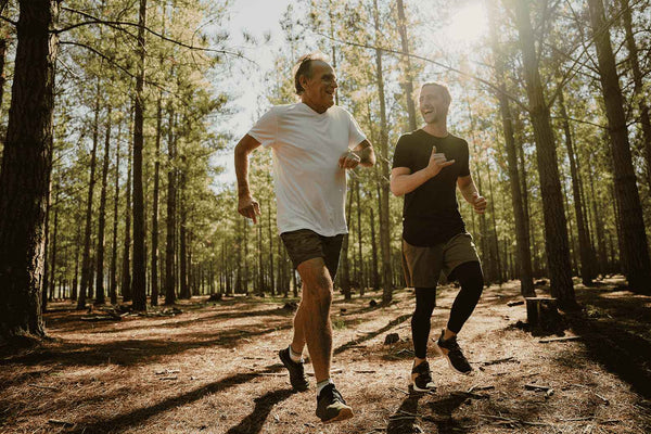 älterer und jüngerer Mann joggen gemeinsam im Wald